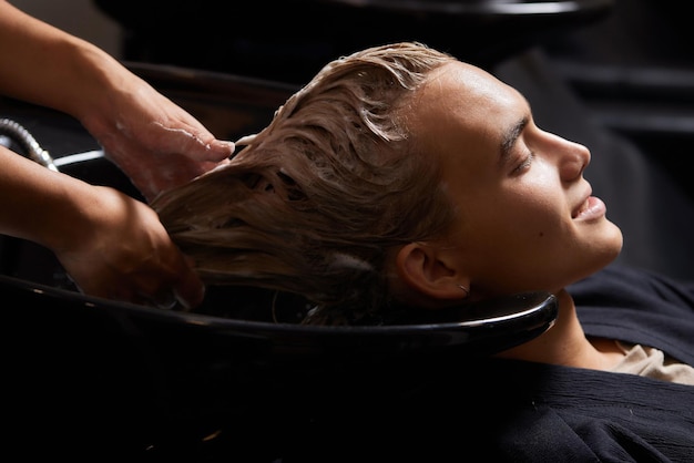 Foto parrucchiere parrucchiere lavaggio capelli cliente giovane uomo rilassante nel salone di bellezza parrucchiere
