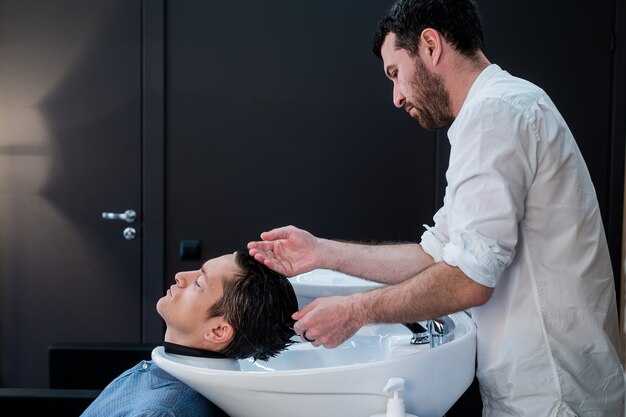 Hairstylist hairdresser washing customer hair