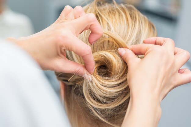 Hairstylist making bride wedding hairstyle