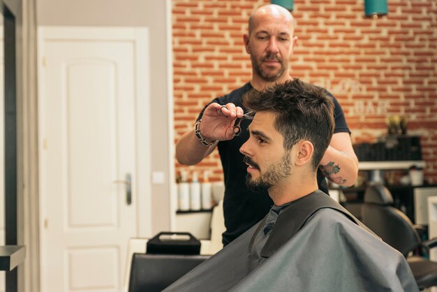 Hairstylist making men's haircut to an attractive man in the beauty salon