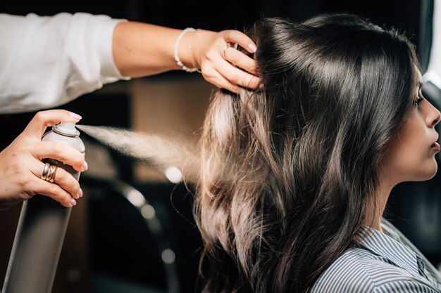 Photo hairstylist spraying womans hair