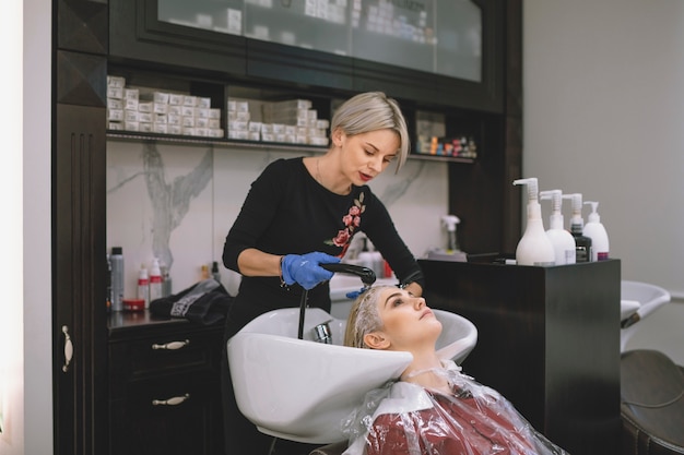 Hairstylist washing hair of customer in parlor