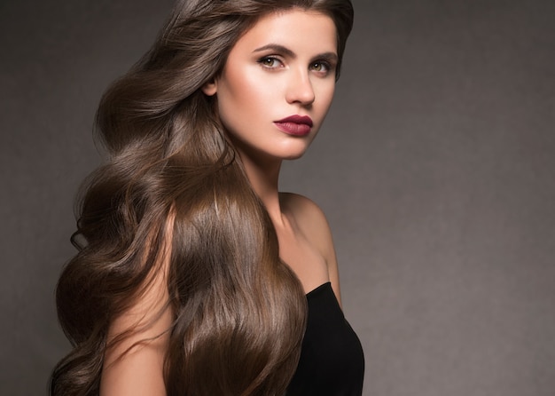 Hairte kapsel model schoonheid vrouw lang krullend brunat. Studio opname.