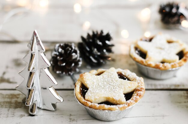 Hak de taart op houten tafel fijn geserveerd met decoratieve kerstboom, dennenappels en lichten