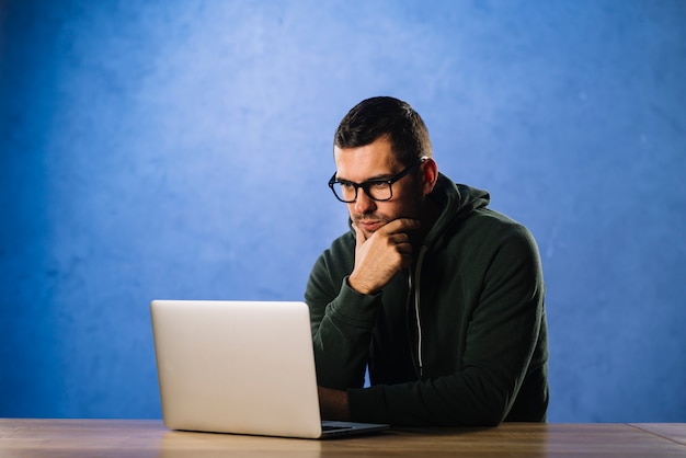 Hakker met glazen die laptop bekijken