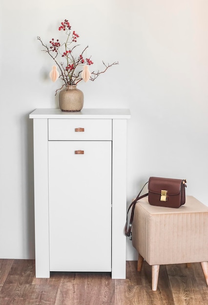 Hal interieur witte houten ladekast en een zachte poef op een houten vloer in een lichte kamer