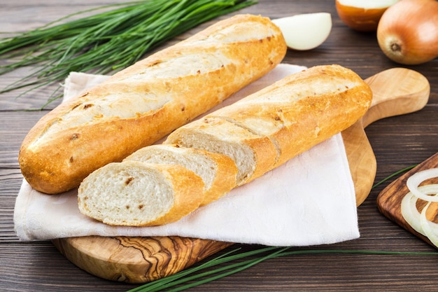 Фото Половина лукового багета на деревянном фоне французского хлеба