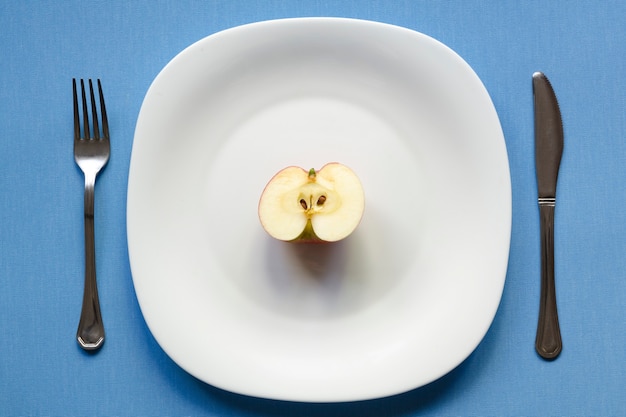 Half an apple on the white plate with blue tablecloth background