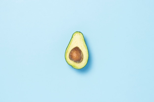 Half avocado on a blue background. Healthy eating concept. Minimalism. Flat lay, top view.