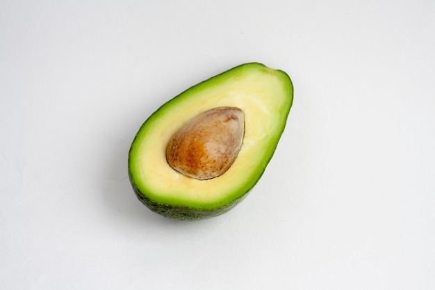 Mezzo avocado con una pietra, isolato su un bianco