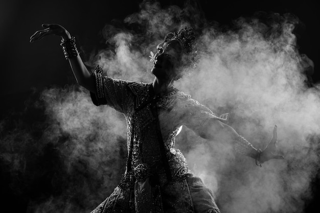 Half body of asian woman wear thai traditional costume dancer\
dress silhouette shadow khon dance is act play royal of thailand\
over black background smoke