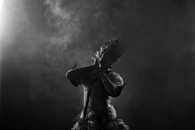 Half body of asian woman wear thai traditional costume dancer
dress silhouette shadow khon dance is act play royal of thailand
over black background smoke