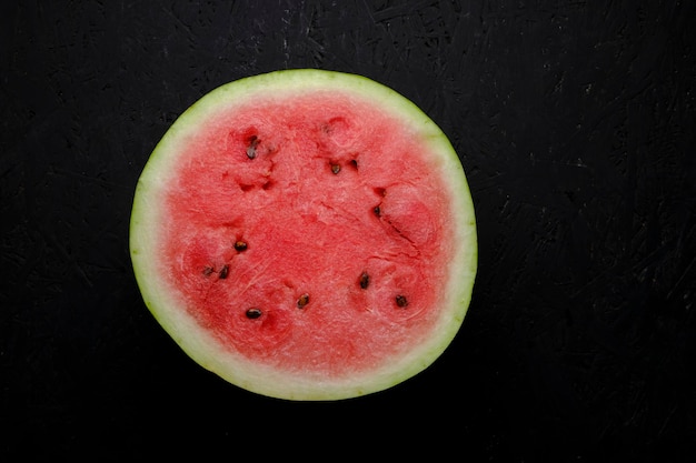 Half bright red cut watermelon black background