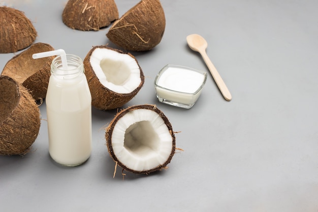 Half a coconut, bottle of coconut milk with straw.