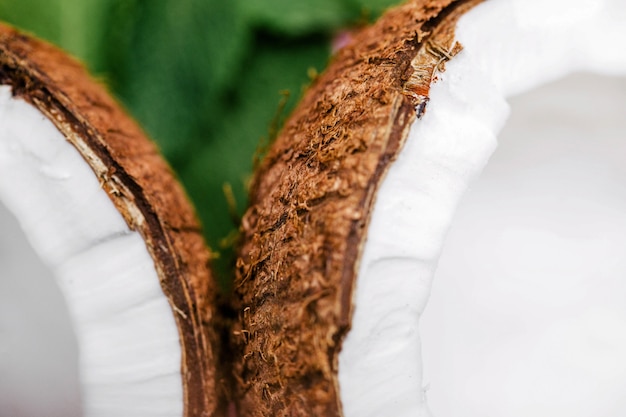 Half of a coconut lies on green leaves