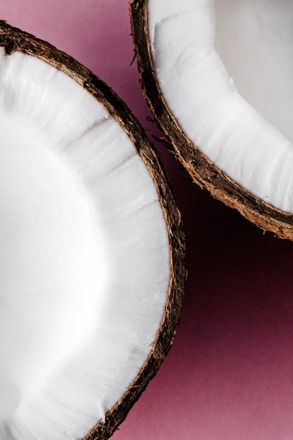 Half of a coconut lies on pink background