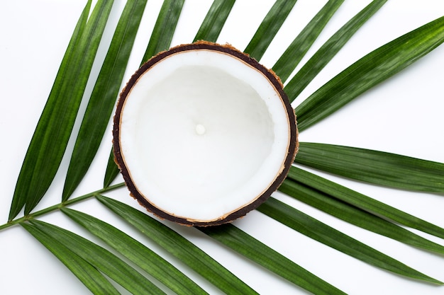 Half coconut on tropical palm leaves. Top view