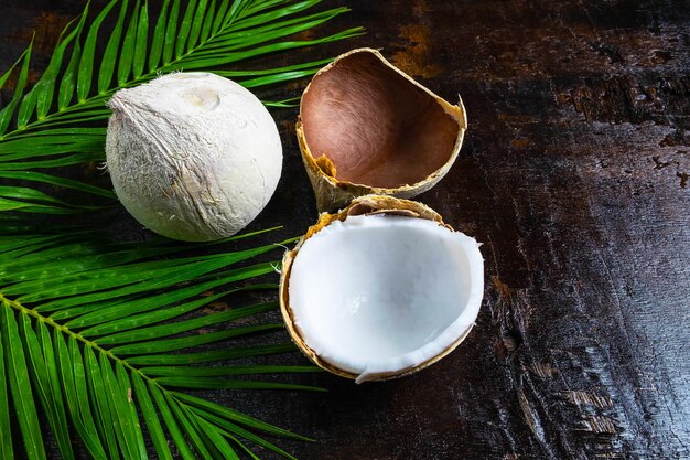 half of coconut with leaves on wooden background