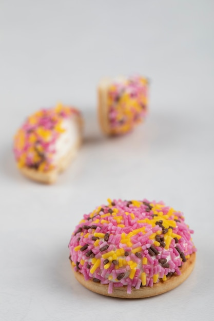Half cut cookies decorated with sprinkles placed on white surface.