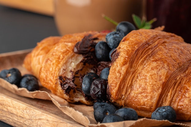 Half cut croissant decorated with fresh berries on wooden table