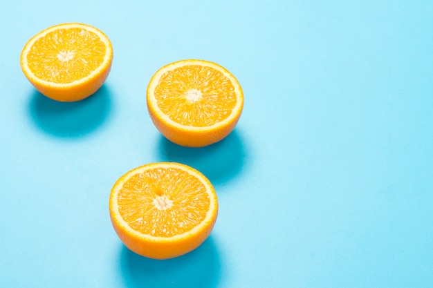 Half cut orange on a blue surface. 