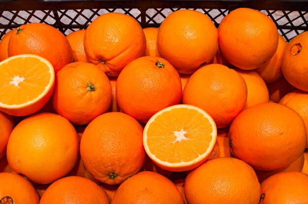 Half cut ripe juicy oranges in a pile of other ones