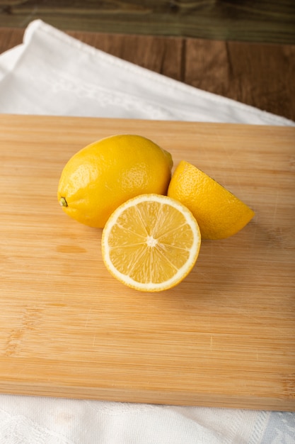 Half cut and whole lemon pieces on a wood board