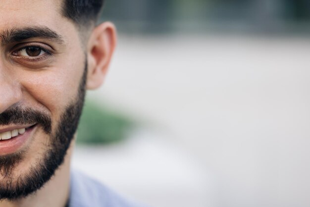 Half face of bearded man with brown eye while standing outdoors portrait of male looking to camera