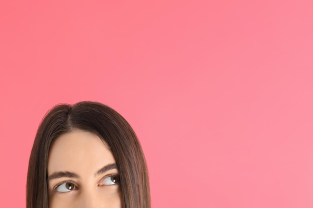 Half face of a young girl on a pink background