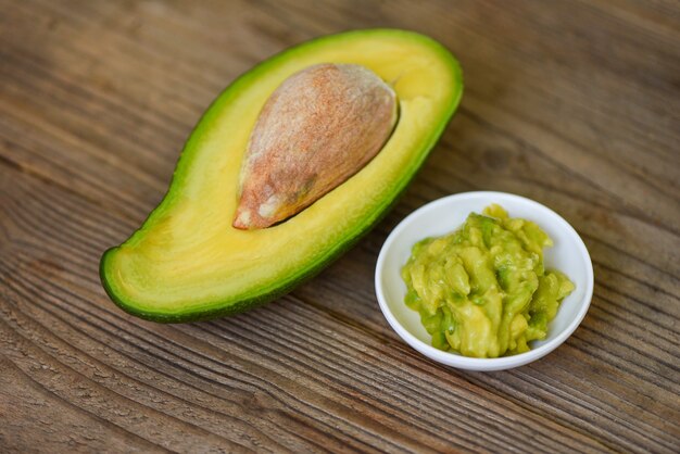 Half gesneden avocado en avocadodipdip fijngestampt op houten achtergrond