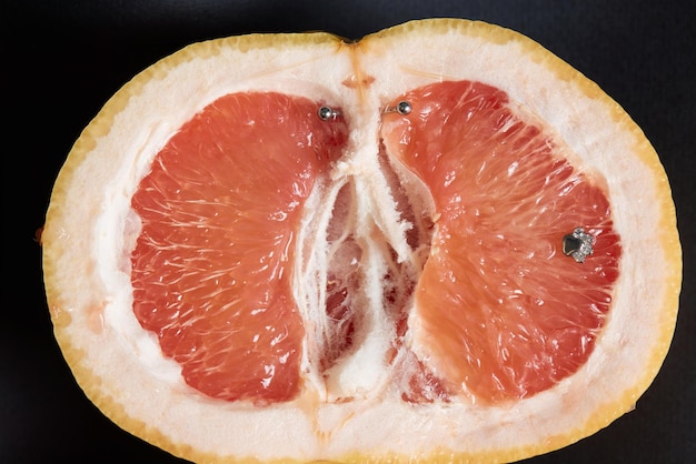 Half of grapefruit with vertical barbell piercing on a background