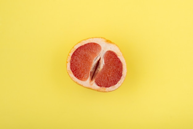 Half grapefruit on a yellow surface