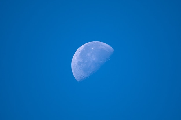 Half illuminated moon on blue sky