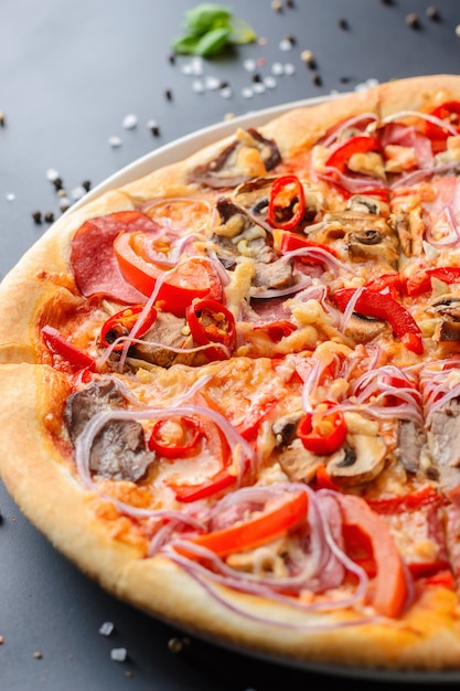 暗い背景にイタリアのピザと新鮮なバジルの葉の半分をクローズアップ。