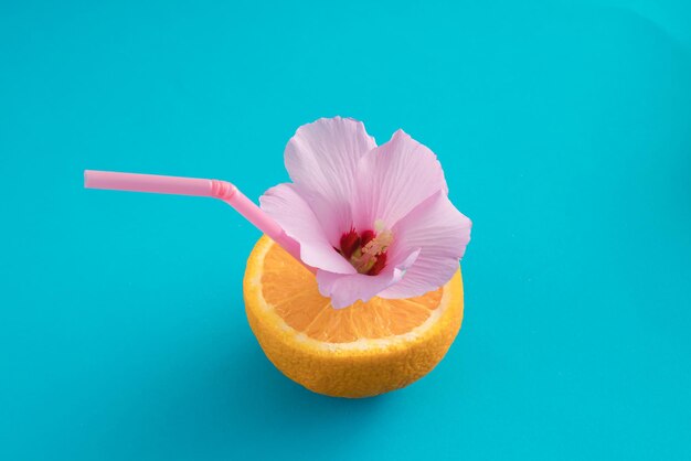 さわやかな夏のカクテルとしてストローと花と半分ジューシーなオレンジ