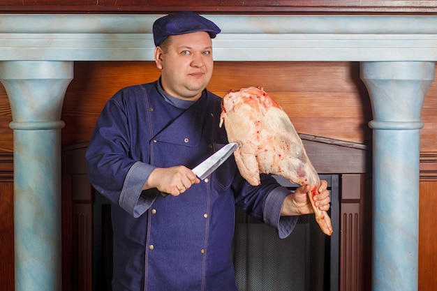 Half legth shot of thoughtful male chef, holds very big red raw piece of meat