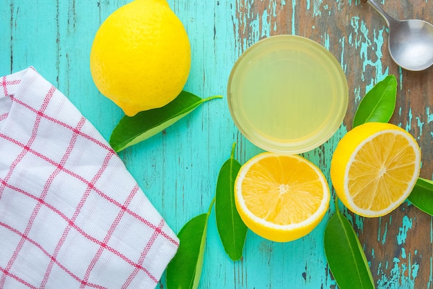 Half lemon and lemon juice squeeze in a small cup place on an old green wooden table