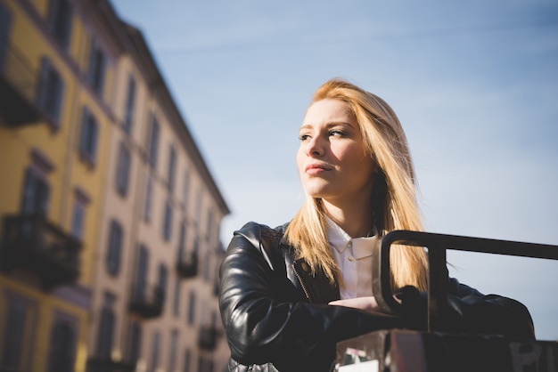 Half lengteprofiel van de jonge mooie vrouw van het blonde rechte haar in de stad