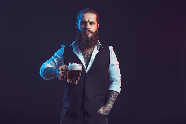 Mezza lunghezza dell'uomo barbuto che tiene un boccale di birra guardando la fotocamera su sfondo nero