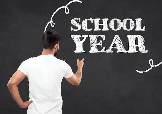 Half-length close up portrait of young hindoo man in white shirt on dark background. Human emotions, education, back to school, sales, advertising concept. Pointing on words SCHOOL YEAR.