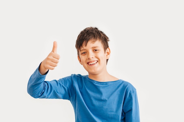 Поясной эмоциональный портрет кавказского мальчика-подростка в синей футболке. Удивленный подросток смотря камеру. Красивый счастливый ребенок, изолированные на белом фоне.