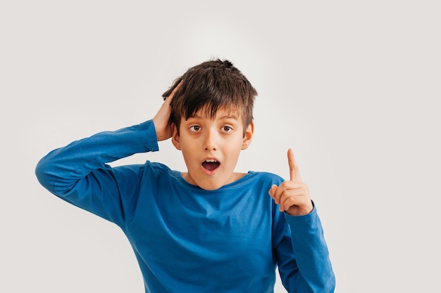 Half-length emotional portrait of caucasian teen boy wearing blue t-shirt. Surprised teenager looking at camera. Handsome happy child, isolated on white background.