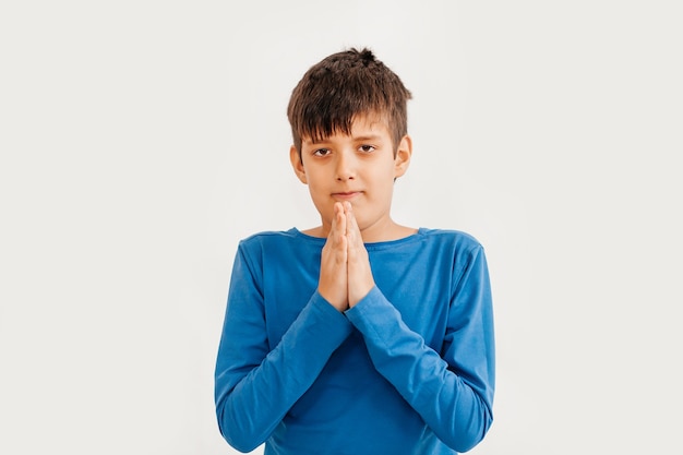 Half-length emotional portrait of caucasian teen boy wearing blue t-shirt. Surprised teenager looking at camera. Handsome happy child, isolated on white background.