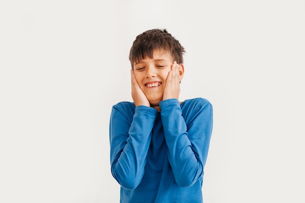 Half-length emotional portrait of caucasian teen boy wearing blue t-shirt. Surprised teenager looking at camera. Handsome happy child, isolated on white background.