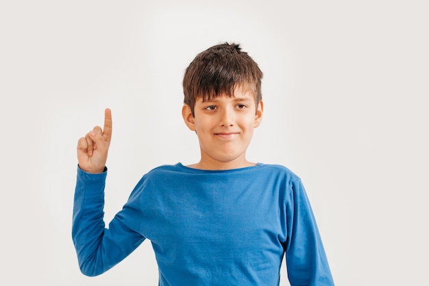 Half-length emotional portrait of caucasian teen boy wearing blue t-shirt. Surprised teenager looking at camera. Handsome happy child, isolated on white background.