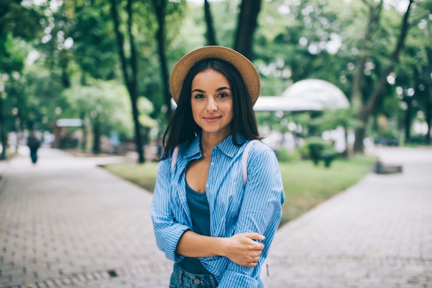 Half length portrait of attractive trendy dressed woman posing\
outdoors and looking at camera