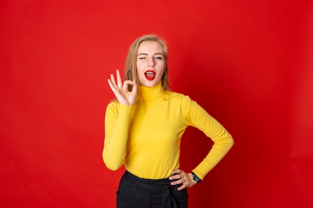 Half- length portrait of joyful  girl showing ok gesture