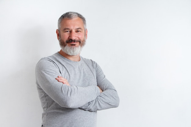 Half-length portrait of a serious gray-haired bearded man in a gray t-shirt 