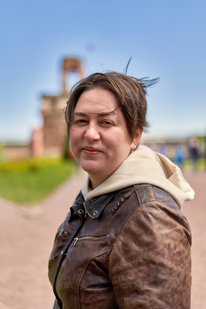 Half length portrait of a young woman in a brown shorthaired leather jacket. Vertical shot