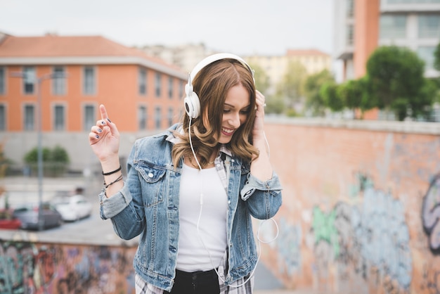 Half length of young handsome caucasian blonde straight hair woman listening music with headphones